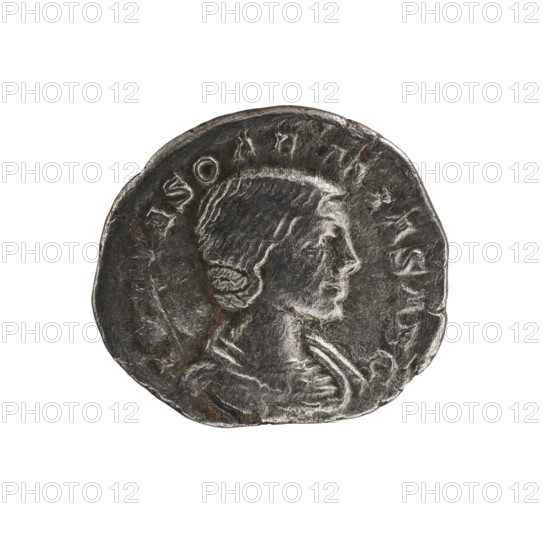 Denarius, Elagabalus 204–222; Roman emperor 218–222. Issuer: Julia Soaemias 180–222; Augusta 218–222. Obverse: IVLIASOAEMIASAVG — Draped bust of Julia Soaemias facing right, pearl border. Reverse: VENVSCAELESTIS — Venus seated on a throne facing left, holding an apple in her right hand and a sceptre in her left; at her feet a child with outstretched arms, pearl border. Rome, 218–222. Coin; diameter 17.5–19.0 mm; weight 2.80 g., A circular metallic object with a worn, uneven edge showing a side-profile relief of a person with short hair and a visible ear, the figure facing right and wearing draped clothing; the surface shows textured, scratched areas and slight discoloration with darker and lighter gray tones and small patches of brownish rust.