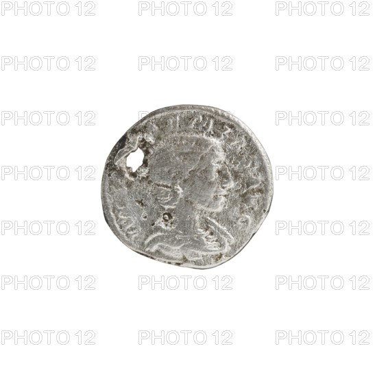 Denarius with hole, Elagabalus reigned 218–222, issuer: Julia Soaemias 180–222; Augusta 218–222. Obv.: IVLIASOAEMIASAVG — Draped bust of Julia Soaemias facing right, pearl border. Rev.: VENVSCAELESTIS — Venus seated on a throne facing left, holding an apple in her right hand and a sceptre in her left; at her feet stands a child with outstretched arms, pearl border. Rome, c. 218–222 CE. Coin; diameter ~17–18 mm; weight 2.35 g., A round, worn metallic object with a rough, pitted surface and an irregular edge, shown against a plain white background; the metal appears silver-gray with darker gray areas in the crevices and lighter silvery highlights on raised portions; the surface shows a faint, worn relief suggesting a profile and ornamental details, plus a small irregular hole near one edge; overall the object looks textured, tarnished, and uneven in color with variations of silver and gray.