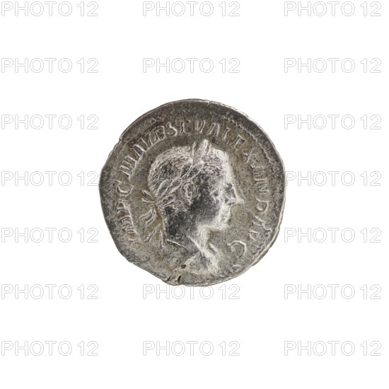 Denarius; personifications; Alexander Severus Roman emperor, 222–235 — iconography: Salus. Obv.: Bust of Alexander Severus with laurel wreath and paludamentum facing right, pearl rim; inscription IMPCMAVRSEVALEXANDAVG. Rev.: Salus sits on a throne facing left, in her right hand she holds a patera feeding a snake coiled around an altar, her left elbow rests on the back of the throne, pearl rim; inscription PMTRPII COSPP. Date: 223, Rome. Roman Empire 27 BC–476. Coin; diameter c. 17.0–17.5 mm; weight 2.70 g., A round metallic coin with a worn surface showing a raised profile of a person's head facing right, with short hair and what appears to be a small wreath or tied band around the back of the head; the coin's edge is rimmed and irregular, and there is a ring of raised decorative marks around the portrait; visible colors include shades of silver, gray, dark gray, and a few darker tarnished spots.