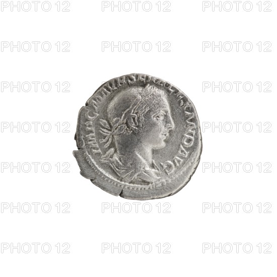 Denarius, Alexander Severus Roman emperor; 222–235 — iconography: personifications, Virtus. Obverse: IMPCMAVRSEVALEXANDAVG — Bust of Alexander Severus with laurel wreath and paludamentum facing right, pearl rim. Reverse: VIRTVSAVG — Virtus in military garb and helmet facing right, holding a spear point down in his right hand, resting his left hand on a shield at his feet, pearl rim. Date: 222–228. Roman Empire; Rome. Coin; diameter 18.0–18.5 mm; weight 2.65 g., A single round metallic coin with a worn surface and a raised profile of a person's head facing right, showing facial features and hair tied at the back, surrounded by a raised border and decorative rim; the coin appears silver-gray with darker gray shading in recessed areas and lighter highlights on raised surfaces, and there are a few irregular chips and rough edges on the coin's perimeter.