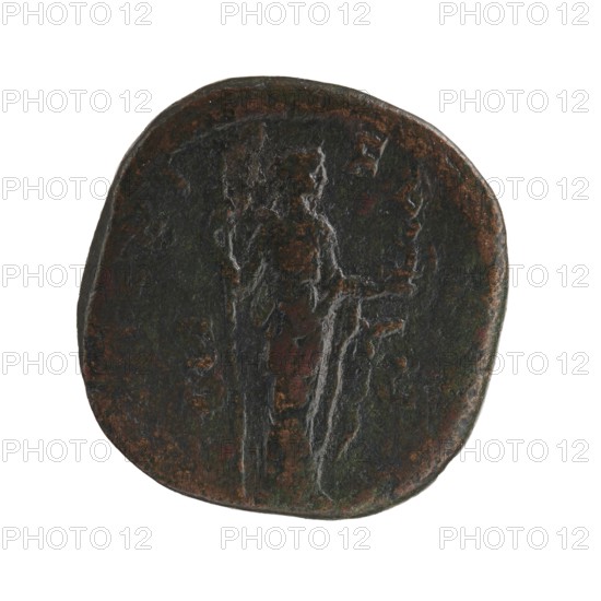 Sestertius of Alexander Severus 208–235; Roman emperor 222–235. Obverse: portrait of Julia Mamaea ca. 180–235; Augusta 222–235 — iconography of Julia Mamaea; Roman deities: Venus. Date: 225–235. Roman Empire 27 BC–476, Rome. Coin; diameter 28.5–29.0 mm; weight 18.7 g., A worn round object with uneven edges showing a raised figure in low relief against a dark surface; the object displays a mix of dark brown, black, and greenish tones with areas of reddish-brown patina, and the figure appears elongated with vertical grooves and softer highlights where the surface is more polished.