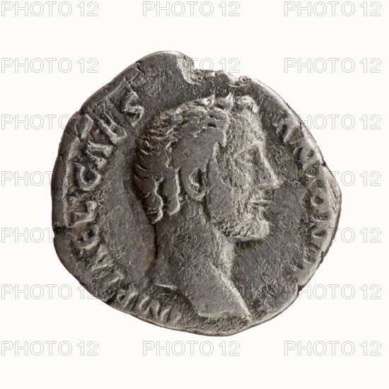 Denarius, 138 CE. Obverse: head of Antoninus Pius without a cap to the right, legend IMP T AEL CAES - ANTONINVS; Reverse: Minerva stands left, in her outstretched right hand she holds Victoria, in her lowered left hand she holds a spear with the head upwards and a shield resting on the ground, legend TRIB - POT COS. Issued under Hadrian emperor 117–138 and Antoninus Pius emperor 138–161; caesar 138. Roman, Rome. Coin; diameter 16.0–17.0 mm; weight 3.06 g; axis 165°., A worn round metallic object with an irregular edge depicting a raised profile of a person's head facing right; the head shows short textured hair, a prominent nose, and a defined jaw and neck. The surface is rough and pitted with areas of wear and small scratches. The object has a metallic gray color with darker gray shadows and some lighter gray highlights on raised areas. The background is plain and white, contrasting with the coin-like object.