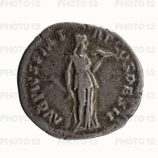 Denarius of Antoninus Pius 86–161; Roman Emperor 138–161. Obverse: head of Antoninus Pius uncovered to the right, legend IMP T AEL CAES HADRI - ANTONINVS. Reverse: Diana standing to the right, holding a bow in her outstretched left hand and an arrow in her lowered right hand, legend AVG PIVS PM T - RP COS DES II. Iconography: Diana standing; attributes: bow, arrows. Date: 138. Place of minting: Rome, Roman Empire. Coin type: silver denarius. Dimensions: diameter ~17–18 mm, weight 2.58 g, axis 180°., A round metallic object with a worn, dark gray surface showing lighter gray highlights, featuring a raised, stylized standing human figure in the center wearing a draped garment and holding an object in one hand; the edges are irregular and slightly dented, and the background shows areas of uneven texture and subtle greenish-brown patina.