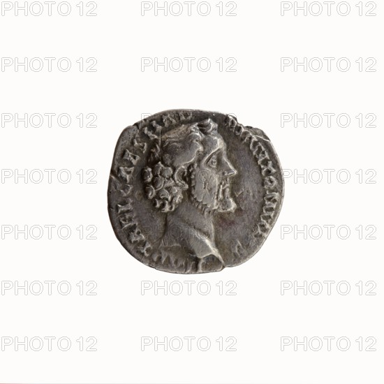 Denarius, Antoninus Pius 86–161; Roman Emperor 138–161. Obverse: head of Antoninus Pius uncovered to the right; legend IMP T AEL CAES HADRI ANTONINVS around. Reverse: Aequitas standing left, holding scales in his outstretched right hand and a cornucopia in his left; legend AVG PIVS PM TR - P COS DFS sic! II around. Iconography: Aequitas, scales, cornucopia, personification. Date: 138. Place: Rome, Roman Empire. Medium/format: coin denarius. Diameter: 16.0–17.5 mm. Weight: 2.92 g. Axis: 180°., A round, worn coin with a raised profile of a bearded man facing right; the coin surface shows textured, uneven wear and a patina in shades of gray and silver with darker gray areas and slight brownish tones; the man's hair and beard are detailed with curls, and there is a raised rim and faint decorative markings around the edge; the background is plain white.