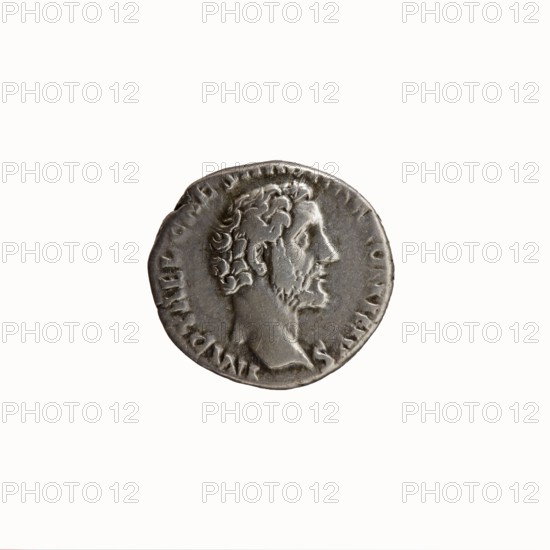 Denarius, Antoninus Pius 86–161; Roman Emperor 138–161. Obverse: head of Antoninus Pius bare, facing right, legend IMP T AEL CAES HADR ANTONINVS around. Reverse: Victoria walking right, holding a wreath in her outstretched right hand and a palm branch in her left, legend AVG PIV S PM TR P COS II around. Dated 139. Rome, Roman Empire. Coin; diameter 15.0–17.0 mm, weight 3.88 g, axis 180°., A round metallic coin with a worn surface showing a raised profile of a bearded man facing right, his hair and beard rendered with textured curls; the coin appears silver-gray with darker gray patina in recessed areas and lighter highlights on raised features, and it sits against a plain off-white background.