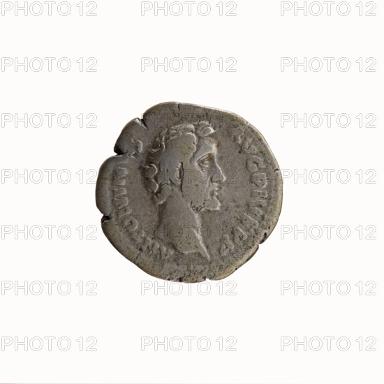 Denarius, Antoninus Pius 86–161; Roman Emperor 138–161. Obverse: Head of Antoninus Pius uncovered facing right, inscription ANTONINVS AVG PIVS PP. Reverse: Container modius with ears of corn and poppy-head, inscription TR P COS II. Iconography: cereals, ears of corn, modius, poppy-heads. Date: 139. Place of origin: Rome, Roman Empire 27 BC–476. Medium/format: coin. Dimensions: diameter 17.0–18.0 mm, weight 3.37 g, axis 180 degrees., A round, worn metallic coin with a raised profile of a bearded man facing right, showing detailed hair and facial features; the coin surface is textured with signs of age and small nicks along the edge, and the visible colors include shades of gray, muted silver, and hints of brownish patina.