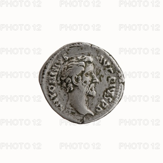 Denarius, Antoninus Pius 86–161; Roman Emperor 138–161. Obverse: Head of Antoninus Pius uncovered facing right, inscription ANTONINVS - AVG PIVS PP. Reverse: Container modius with ears of corn, inscription TR P - COS - II. Date: 139. Place of origin: Rome, Roman Empire. Coin; dia. 18.0–19.0 mm, weight 3.36 g, axis 180°., A round silver-gray coin with a worn profile of a bearded man facing right, showing textured hair and facial features, surrounded by a raised decorative border and a ring of worn markings; the surface shows areas of darker gray and slight greenish tarnish.