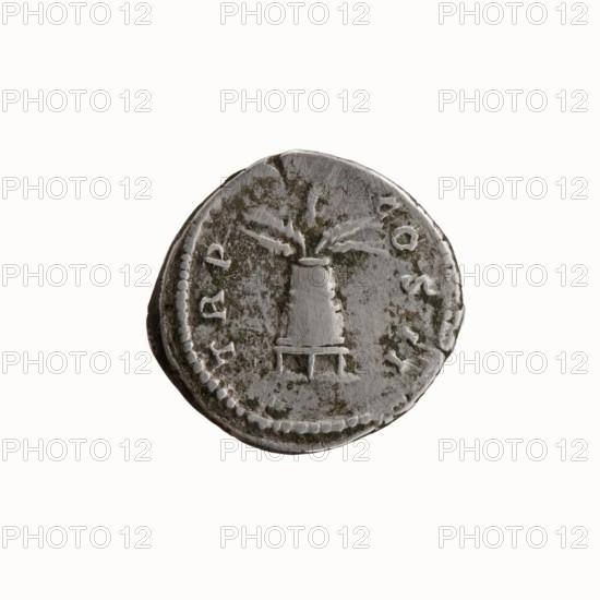 Denarius, Antoninus Pius 86–161; Roman Emperor 138–161. Obverse: Head of Antoninus Pius uncovered facing right; inscription ANTONINVS · AVG · PIVS · PP. Reverse: Container modius with ears of corn; inscription TR P · COS · II. Date: 139. Place of origin: Rome, Roman Empire. Medium: coin; diameter 18.0–19.0 mm; weight 3.36 g; axis 180°., A round metallic coin with a worn, textured surface showing areas of darker greenish discoloration and lighter silver tones, featuring a central raised depiction of a conical object on a small rectangular base and a few radiating lines above it; the coin edge has a dotted border and the surface shows signs of wear and patina.