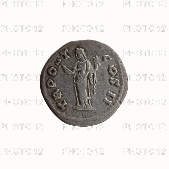 Denarius of Antoninus Pius 86–161; Roman Emperor 138–161, 139 CE. Obverse: head of Antoninus Pius uncovered to the right, legend ANTONINVS AVG PIVS PP. Reverse: Felicitas standing to the left, holding a caduceus in her outstretched right hand and a cornucopia in her left, legend TR P O T COS II. Iconography: caducei, personifications, Felicitas, cornucopias. Roman Empire; minted in Rome. Coin; diameter 18.5–19.0 mm, weight 2.97 g, axis 180°., A round metal coin with a worn, dark gray surface showing a raised design of a standing human figure draped in a long garment, holding an object in each hand; the figure faces forward with visible contours of head, shoulders, and the folds of the clothing. The coin edge is irregular and slightly uneven, and there is a border of raised, indented marks around the perimeter. The background is a plain off-white. Colors visible include dark gray on the coin and off-white in the background.