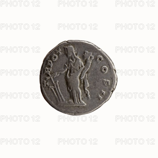Denarius, Antoninus Pius 86–161; Roman emperor 138–161. Obverse: head of Antoninus Pius uncovered to the right; legend ANTONINVS · AVG · PIVS · PP. Reverse: Fortuna standing left, holding a rudder in her right hand and a cornucopia in her left; legend T · R · POT · COS II. Iconography: Fortuna, personifications, horns of plenty, rudders. Roman Empire, 139, Rome. Coin. Diameter 17.0–17.5 mm; weight 3.22 g; axis 180°., A round, worn metallic object with a dark gray patina showing a raised, low-relief scene of two standing humanlike figures, one in front holding an elongated object and the other slightly behind with an arm raised; the surface has irregular edges and subtle scratches, and the visible colors are dark gray, lighter gray highlights, and faint off-white reflections against a plain pale off-white background.
