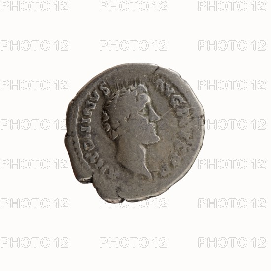 Denarius, Antoninus Pius 86–161; Roman emperor 138–161. Obverse: head of Antoninus Pius, bare, right; legend ANTONINVS AVG PIVS PP. Reverse: Libertas standing left, holding a liberation cap pileus in right hand and a long staff vindicta in left; legend TR POT COS II 139. Iconography: personification Liberty Libertas, pileus, vindicta. Roman coin; diameter 17.5–18.0 mm, weight 2.76 g, axis 165°., A worn round metal coin in gray and silver tones, shown against a plain white background; the coin features a raised profile of a person's head facing right with visible facial contours and short stylized hair, and a textured rim with some irregular edges and small chips; the surface shows scratches, dents, and areas of darker tarnish and lighter highlights, giving an overall aged, uneven appearance.