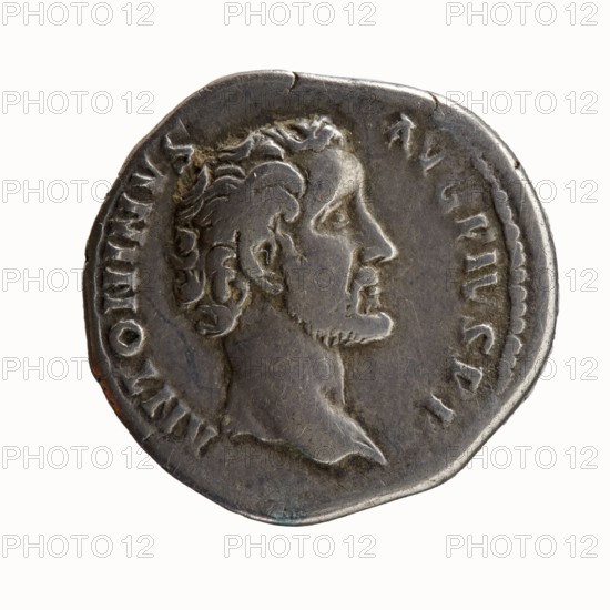 Denarius of Antoninus Pius 86–161; Roman Emperor 138–161. Obverse: Head of Antoninus Pius uncovered to the right, legend ANTONINVS · AVG PIVS · PP. Reverse: Pax standing left, holding a twig in his right hand and a cornucopia in his left, legend TR · POT · COS II. Minted Rome, 139. Roman Empire. Coin; diameter 17.0–18.0 mm; weight 3.27 g; axis 180°., A round metal coin with a worn, raised profile of a man's head facing right, showing short curly hair and a short beard, surrounded by an outer raised rim and a ring of small raised marks; the coin surface appears aged with uneven texture and slight dents along the edge, and visible colors include gray, silver, dark gray, and hints of brown.