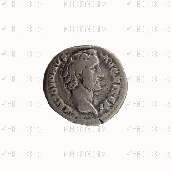Denarius, Antoninus Pius 86–161; Roman emperor 138–161. Obverse: head of Antoninus Pius uncovered to the right, legend ANTONINVS · AVG · PIVS · PP. Reverse: Pax standing left, holding a branch in his right hand and a cornucopia in his left, legend TR · POT · COS II. Iconography: Pax, branches, cornucopias, personifications; issuer: Antoninus Pius. Date: 139. Place of manufacture: Rome, Roman Empire. Object type: coin denarius. Dimensions: diameter 17.0–17.5 mm; weight 2.67 g; axis 180°., A round metallic object with a worn, irregular edge showing a raised profile of a person's head in relief, facing right; the surface has areas of darker and lighter gray with patches of wear and small scratches, and the profile shows textured hair and facial features in low relief; the object sits against a plain off-white background.