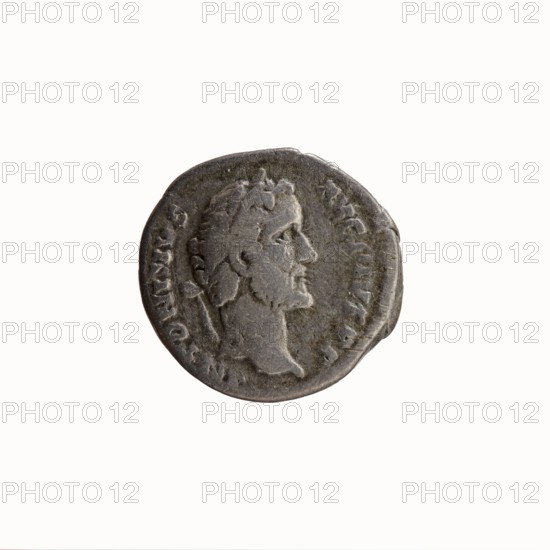 Denarius, Antoninus Pius 86–161; Roman emperor 138–161. Aw: Head of Antoninus Pius in a laurel wreath facing right, legend ANTONINVS·AVG·PIVS·PP. Rw: Two hands clasping, holding a winged caduceus and ears of corn, legend TR P·OT C·OS·II. 139 CE. Rome. Coin; diameter 17.0–18.0 mm, weight 3.26 g, axis 180°. Iconography: caduceus, hands holding a caduceus, ears of corn; symbols of consent/union., A circular metallic object with a worn surface showing a raised profile of a person's head in relief, facing right, surrounded by a raised rim and faint surrounding decorative elements; the object appears mainly gray with darker and lighter gray variations and subtle brownish-gray patina, all set against a plain off-white background.