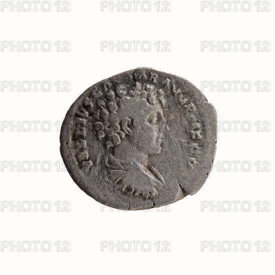 Denarius, Antoninus Pius 86–161; Roman emperor 138–161. Obverse: Head of Antoninus Pius in a laurel wreath to the right, legend ANTONINVS AVG PI - VS PP TR P COS III. Reverse: Bust of young Marcus Aurelius in cloak paludamentum, without headgear, right, legend AVRELIVS CAESAR AVG PII F COS. Ca. 140. Roman Empire. Rome mint. Coin. Diameter 17.0–19.0 mm. Weight 2.74 g. Axis 180°., A round, worn coin with a raised profile of a person facing right in the center, showing textured hair and a visible neck and shoulder area, surrounded by a ring of raised markings; the coin surface is uneven with small chips and cracks at the edges, and the color is predominantly gray with darker gray areas and subtle hints of brownish tones.