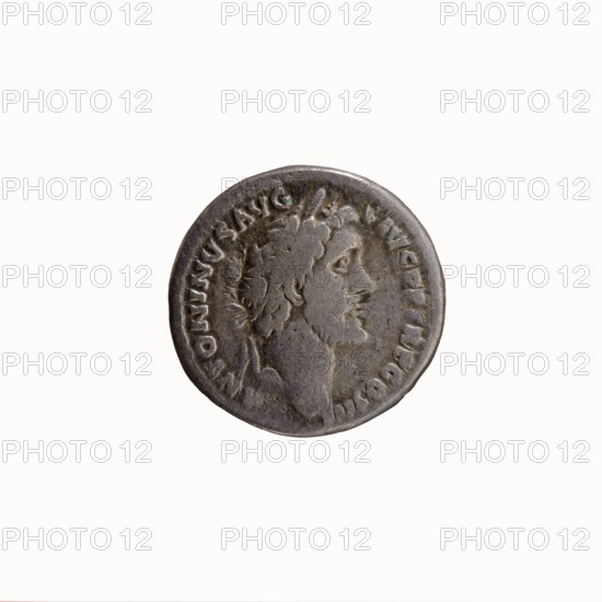 Denarius, Antoninus Pius 86–161; Roman emperor 138–161 issuer: Marcus Aurelius 121–180; Roman emperor 161–180 Caesar 139–161. Obverse: Head of Antoninus Pius with laurel wreath facing right; legend ANTONINVS AVG PIVS PP TR P COS III. Reverse: Bust of young Marcus Aurelius in cloak paludamentum, without headgear, right; legend AVRELIVS CAES AVG PII F COS. 140 CE, Roman Empire; Rome mint. Coin; diameter 17.0–17.5 mm, weight 2.73 g, axis 195°., A circular metallic object with an aged, worn surface showing a raised profile of a bearded man facing right; the coin has a textured rim and areas of wear and patina giving darker and lighter grey tones, with subtle greenish spots and brownish discoloration in places.
