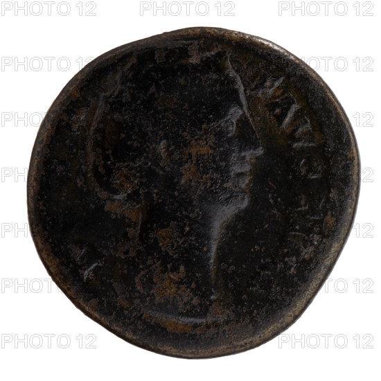 Sestertius; obverse: Bust of Faustina I in drapery facing right, inscription DIVA · FAVSTINA around; reverse: Vesta standing left, in her outstretched right hand she holds a statuette of Athena palladion, in her left a scepter, inscription AVGVSTA all around, in SC fields. Issuer: Antoninus Pius 86–161, posthumous portrait of Faustina the Elder 98–141. Roman deity: Vesta; attribute: palladium, torches. After 141 CE. Roman Empire; Rome. Coin sestertius, diameter 29.0 mm, weight 19.70 g, axis 345°., A round, worn coin-like object with a dark, almost black surface mottled with brown patches and lighter brown corrosion; a faint raised profile of a face in side view is visible against the textured background, with smoother highlights on the cheek and forehead, and a rounded rim that shows subtle variations in dark brown and black tones.