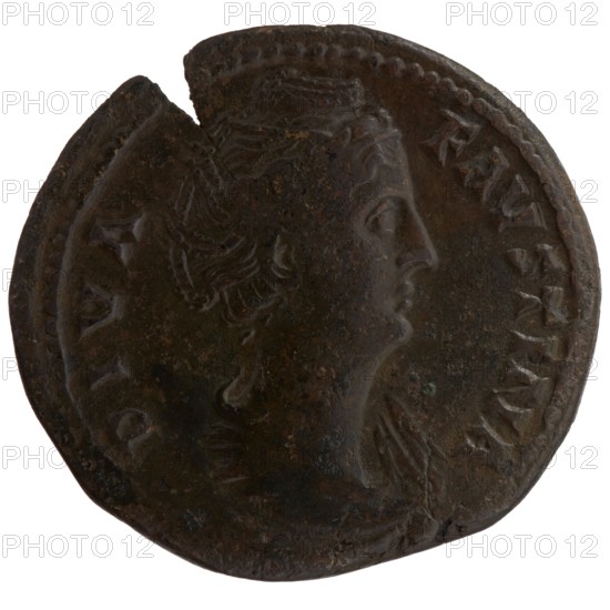 Sestertius coin, posthumous issue for Faustina the Elder 98–141; Roman empress 138–141, issued under Antoninus Pius 86–161; Roman emperor 138–161. Obverse: bust of Faustina I draped, facing right, legend DIVA FAVSTINA. Reverse: Juno veiled and diademed, standing left, holding a patera in her outstretched right hand and a long scepter in her left; legend IV-NO around, in SC fields. After 141 CE, Roman Empire; Rome mint. Coin: diameter 32.0–34.0 mm, weight 21.55 g, axis 0°., A round dark brown metal coin with uneven edges showing a profile of a person's head facing right; the head has detailed hair and a small crown or headband, and the coin surface shows areas of darker and lighter brown patina with some subtle greenish spots and worn textures.