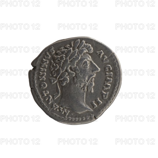 Denarius, Marcus Aurelius 121–180; Roman emperor 161–180. Obverse: Head of Marcus Aurelius with laurel wreath facing right, legend M ANTONINVS - AVG IMP II. Reverse: Minerva standing left, holding a branch in her right hand, left hand supporting a round shield against which a spear is leaning, legend TR P XVIII - COS III. Date: 163–164. Place of origin: Rome, Roman Empire. Type: coin denarius. Materials/measurements: weight 3.10 g; diameter 17–18 mm; axis 180°., A round metallic coin with a worn surface showing a raised profile of a bearded man facing right wearing a laurel wreath, surrounded by raised edging and decorative dots along the rim; the coin appears primarily gray with darker gray shadows and lighter gray highlights, and shows areas of wear and small imperfections along the edge.