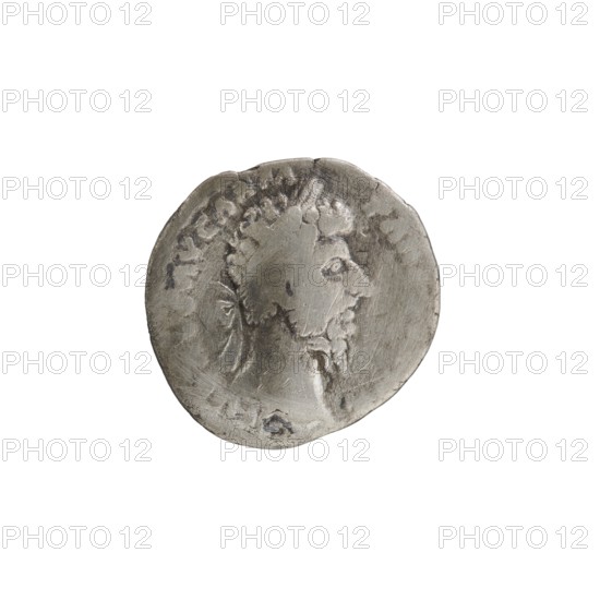 Denarius of Lucius Verus 130–169; Roman emperor 161–169. Obverse: Head of Lucius Verus in a laurel wreath facing right; inscription L VERVS AVG ARM - PARTH MAX. Reverse: Pax standing left, holding a branch in his right hand and a cornucopia in his left; inscription TR P VI IMP IIII COS II. Iconography: twigs, personifications Pax, cornucopias. Episode: PAX, 166, Roman Empire; mint: Rome. Coin; diameter 17.5–18.5 mm, weight 2.95 g, axis 195°., A round metallic object with a textured, worn surface showing the raised profile of a person facing right, with short curly hair and facial hair; the object has irregular edges and areas of darker patina and lighter polished tones in shades of gray and silver, with some subtle darker gray marks and scratches across the surface.