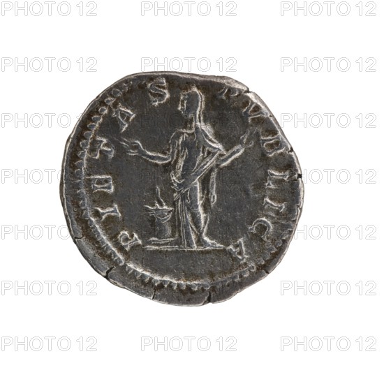 Denarius of Septimius Severus 146–211; Roman emperor 193–211. Issuer: Julia Domna ca. 160–217; Roman empress 193–211. Obverse: IVLIA AVGVSTA, bust of the empress facing right. Reverse: PIETAS PVBLICA, Pietas standing left in front of an altar with raised arms. Date: 196–211. Place of origin: Rome, Roman Empire. Type: coin denarius. Diameter: 17.5–18.5 mm. Weight: 3.08 g., A round metal coin with a dark gray to silvery surface showing wear and scratches, featuring a raised depiction of a standing human figure in draped clothing with arms extended and a small raised object near the figure’s feet; the coin edge is irregular and slightly chipped, with a contrast between darker recessed areas and lighter worn highlights.