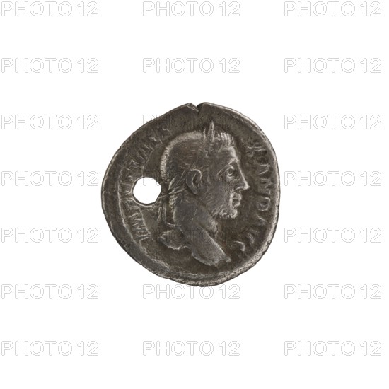 Denarius with hole, Alexander Severus 208–235; Roman emperor 222–235 issuer; obverse/portrait of Alexander Severus; reverse: Roman deity Victoria; iconography of Alexander Severus, dated 228–231; Roman Empire, Rome; coin; diameter 18.0–19.0 mm; weight 2.80 g., A round, worn metallic coin in dark gray and silver tones with a raised profile of a bearded man facing right, a few textured areas indicating hair and facial features, a small circular hole near the left edge of the coin, uneven and slightly irregular outer rim, and subtle highlights and shadows across the surface.