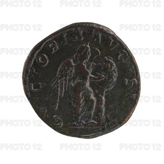 Sestertius; Roman deities; Victoria; Alexander Severus Roman emperor, 222–235 — iconography, 228–231; Roman Empire 27 BC–476, Rome; coin; diameter 27.5–29.0 mm; weight 16.70 g, A dark circular object with worn edges showing a patina of green, brown, and black occupies the center; its surface has raised, weathered relief depicting a winged figure standing and holding a rounded object, with textured details on the wings and drapery, and the overall lighting highlights subtle reddish-brown spots and metallic sheen against a white background.