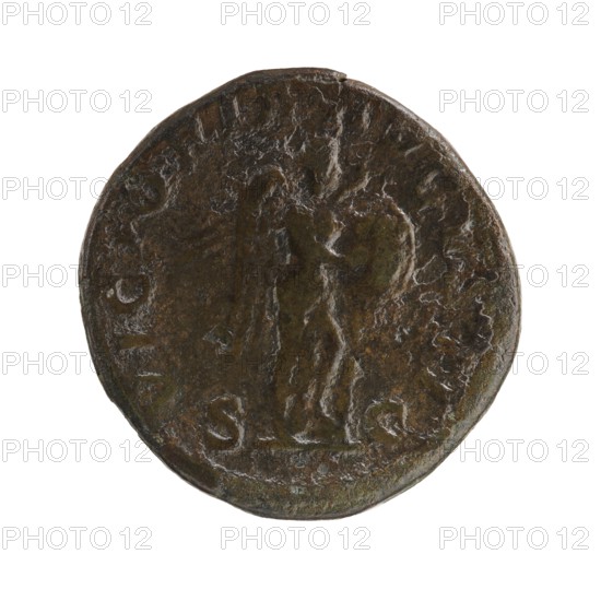 sestertius; Roman deities; Victoria mythology; Alexander Severus Roman emperor, 222–235 — iconography; 228–231; Roman Empire 27 BC–476 place of origin: Rome; coin; diameter 28.5–30.0 mm; weight 18.25 g, A round, worn coin with a textured surface showing a raised figure in the center next to a tall vertical object, all rendered in dark brown and greenish-brown tones with areas of lighter brown highlights and some darker greenish spots, and a slightly irregular edge around the rim.