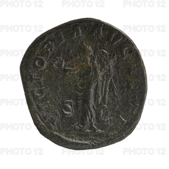Sestertius; Roman deities; Alexander Severus Roman emperor, reign 222–235; iconography: Victoria mythology; dated 228–231; Roman Empire 27 BC–476, Rome; coin; diameters: 28.5 mm and 31.0 mm; weight 20.70 g., A round, worn metal coin with a dark greenish-brown patina showing a faint raised figure standing in the center, draped in flowing garments and facing sideways; the figure appears to have an arm extended and holds a small object in the other hand. The coin surface is textured and irregular with areas of lighter and darker green and brown, and the edges are uneven and slightly rounded. There are traces of raised marks and shapes around the perimeter, and the overall color palette includes dark green, brown, and hints of gray.
