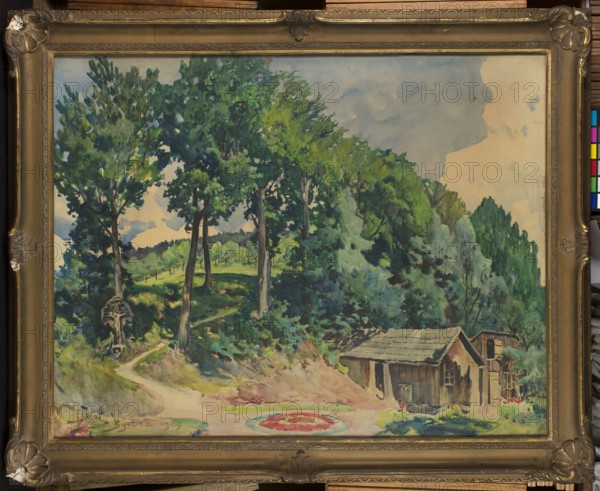 Garden in Bystra, Julian Falat 1853–1929, watercolor drawing, 1909; subject: gardens in Bystra Silesian Voivodeship, Bielsk County with landscapes and roadside shrines; dimensions: height 107 cm, width 140 cm., A framed landscape painting showing a wooded hillside with a group of tall trees in the foreground and dense green foliage covering the slope, with a few lighter green and bluish-green leaves visible among darker greens; the sky appears pale blue with soft beige and gray wash areas; a dirt path winds from the foreground into the trees, rendered in sandy beige and light brown tones; near the lower right a small wooden structure with a pitched roof sits at the base of the hill, painted in brown and muted tan with darker brown accents; a circular painted area with red and pink hues surrounded by pale green is visible on the ground near the center foreground; a carved wooden cross or shrine stands beside the path on the left, in earthy brown tones; the painting is contained in an or...