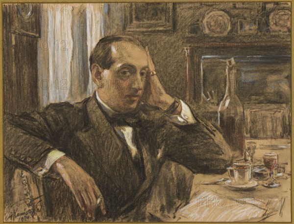 Portrait of Leon Reynel; Antoni Kamienski 1860–1933, draughtsman/author; 1924; pastel; 63 × 77 cm; male portrait of writer Leon Reynel 1887–1931; interiors; filigrees., A seated man wearing a dark suit with a white shirt and bow tie leans with one arm on the back of a chair and the other hand resting against his head; his face has medium skin tones and short dark hair, and he wears a ring visible on one finger. The room shows a table in front of him with a teacup and saucer, a small glass, a larger glass with a dark liquid, and a bottle, all rendered in brown, beige, and muted red tones; the background includes curtains in pale cream and blue-gray, wooden furnishings in dark brown, and decorative plates with pale and warm colors on a shelf. The overall palette uses shades of brown, beige, black, cream, blue-gray, and muted red.