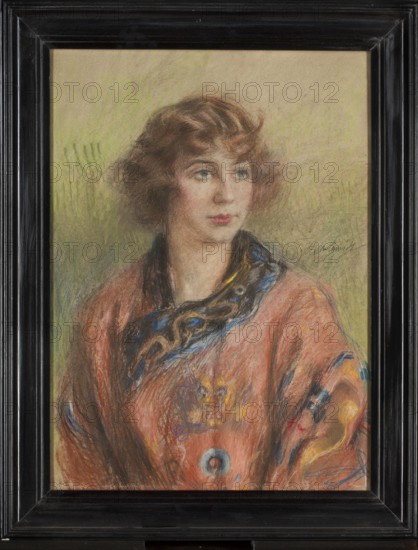 Portrait of a Woman in a Chinese Wedding Robe longpao, Teodor Axentowicz 1859–1938, painter; 1920s; pastel; height 68 cm, width 50 cm. Subjects: female portrait, fashion, Chinese wedding robe., A framed pastel portrait of a young woman shown from the chest up, with wavy brown hair and a fair complexion, looking slightly to the side with a neutral expression; she wears a loose, patterned garment in shades of orange and coral with accents of blue, yellow, and black, and a dark collar or scarf with blue and gold highlights; the background is a muted blend of green and beige tones; the frame visible around the image is black with a glossy finish.
