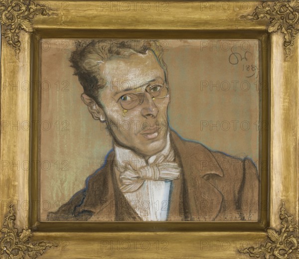 Portrait of Wincenty Parvi, Wyspianski, Stanislaw 1869–1907 author, male portrait, Parvi, Wincenty 1875–1918 — iconography, engineers, Young Poland style, Poland culture, portraits, Polish painting, pastel, drawing, 1899, height 39 cm, width 49.5 cm, A framed portrait of a man shown from the shoulders up wearing a brown jacket and a white shirt with a large bow tie; he has light brown skin and short dark hair with lighter highlights, and he wears round spectacles with small golden accents near the eyes. The man’s face shows subtle shading in beige, brown, and white pastels with outlines in darker tones and a faint blue contour around parts of his silhouette, and his lips and eyes are rendered with muted pink and greenish hues. The background is a flat warm tan color with hints of greenish patina, and the ornate frame surrounding the portrait is a golden color with decorative corner embellishments.