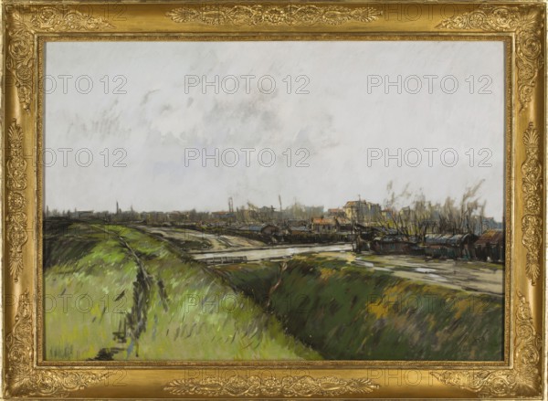 Suburban landscape from the vicinity of Paris, Wyspianski, Stanislaw 1869–1907 painter. Suburban landscapes, Paris, 1893. Pastel; 63.5 × 90.5 cm., A framed painting shows a landscape with a wide expanse of sky occupying the upper area and a low horizon with a distant town. The foreground features a grassy embankment with a path and patches of darker earth, rendered in greens, yellows, and dark browns with strokes of black. Midground areas include a waterway and a narrow bridge with reflections and wet-looking surfaces in muted grays and off-whites. The distant buildings and docks are sketched with small rooflines and slender masts in tones of brown, ochre, muted red, and gray, with thin vertical elements suggesting trees or poles in black and gray. The sky is pale with subtle gray cloud textures. The painting is set in an ornate gold frame with decorative patterns and carved detailing.