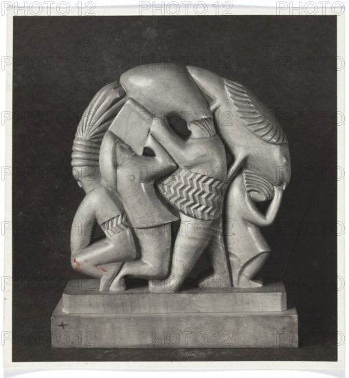 International Exhibition of Decorative Arts and Modern Industries, Paris 1925. Polish Section. Sculpture made at the State School of Timber Industry in Zakopane; photography, photo REP Paris; photographic studio; fl. 1925. Exhibition: International Exhibition of Decorative Arts and Modern Industry, Paris, 1925. Exposition Internationale des Arts Décoratifs et Industriels Modernes Paris; 1925. Paris France. State School of Timber Industry, Zakopane 1918–1939. Polish sculpture; sculpture artist. Photography from nature; art reproduction. Loose print, 1925. Height 15.5 cm; width 14.7 cm., A carved stone sculpture depicting a group of stylized human figures interlocked and overlapping on a rectangular base, shown in a monochrome photograph; the figures have rounded, smooth forms with patterned clothing textures and carved hair or head coverings, some figures appear to be standing while others are crouching, and the composition creates a circular, compact mass; visible colors in the image i...