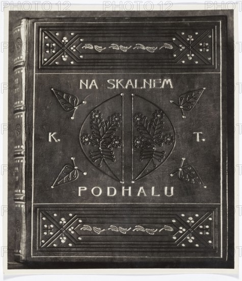 Book binding: Kazimierz Tetmajer, Na skalnem Podhalu. Photo REP. Exhibited at the International Exhibition of Decorative Arts and Modern Industries, Paris, 1925. Subject/notes: bookbinding; literary work by Kazimierz Przerwa Tetmajer 1865–1940. Medium/technique: photography — reproduction of a work of art; photography from nature; loose print. Date: 1925. Place: Paris. Dimensions: height 16.7 cm; width 15.0 cm., The image shows a close-up of a book cover with embossed decorative patterns and central circular motif featuring stylized botanical shapes, surrounded by four leaf-like embellishments and framed by rectangular panels with geometric and floral ornamentation; the cover appears in shades of black, dark gray, and lighter gray with highlights of white on raised elements.