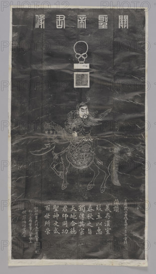 Portrait of the Noble Lord Guan, graphic print, Chinese. Rubbing of stele depicting Guan Yu riding a horse. Title at top: 'Guan sheng di jun xiang' — portrait of Saint Lord Guan (Guan Yu, 160–220), the famous general of the Three Kingdoms Period. Includes one unidentified object (probably 'niu' — a seal with ringed handle) below the title, and the impression of a seal reading 'han shou ting hou zhi yin' — seal of 'han shou ting hou,' a title granted to Guan Yu by Cao Cao (215–220). Depicts Guan Yu wearing a warrior robe, carrying a long-handled knife ('guan gong dao' or 'qing long yan yue da dao'), riding a horse ('chi tu ma', the famed speedy horse given to him by Cao Cao). Inscriptions on the lower left corner. Painting by Li Jintai (Qing artist) copying a model painting. Beginning of the 20th century, China, Xi'an. Graphic print; height 117.0 cm, width 63.0 cm.