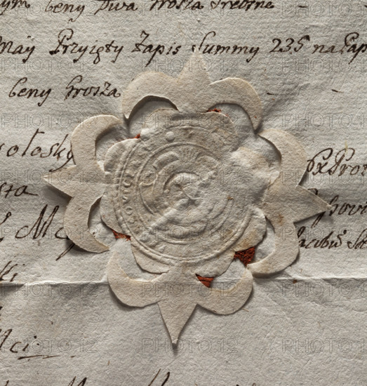 Round seal impression of the town of Proszowice, Kraków Voivodeship. In a round, baroque cartouche with five feathers forming a jewel an illegible drawing of St. John's head on a bowl. In the rim is the inscription: SIGILLUM, ICENSIS., 1777.