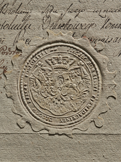 Round imprint of the seal of the Debt Liquidation Commission of the Republic of Poland. On the ermine cloak, under the crown, are two coats of arms cartouches with the Crowned Eagle and the Chaser. Around the rim, the inscription: PIECZEC KOMMISSYI LIKWIDACYINEY DLUGOW RZECZY POSPOLITEY. The document concerns filing a complaint to the court against the Crown Treasury for non-payment of wages. 1775, Poland. seal, A close-up of textured beige paper showing an embossed circular seal with a scalloped outer edge and intricate raised design in the center including a crown and ornamental shapes, surrounded by a raised border; the paper has a few areas of darker beige and brownish stains and a group of flowing dark brown handwritten strokes visible near the top and left edges.
