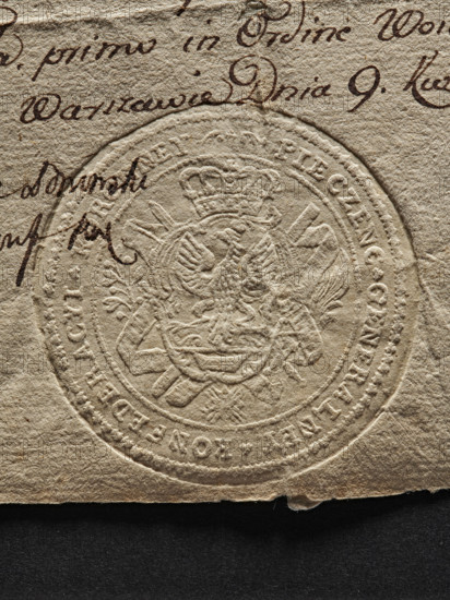 Round imprint of the seal of the General Crown Confederation. In a decorative cartouche, a crowned eagle, below the Lódz coat of arms. Around the cartouche, a red ribbon with the Order of the White Eagle on it. On the sides there are two branches: olive and palm. The inscription around the rim: PIECZENC GENERALNEY KONFEDERACYI KORONNEY. Seal attached to a document regarding financial benefits for the Poznan and Kalisz voivodeships from the Crown Treasury. 1773, Poland., A close-up of textured beige paper with an embossed circular seal showing a crowned double-headed eagle and decorative elements, overlaid by a few dark brown ink pen strokes and cursive marks; the paper edge rests on a flat black surface, and visible colors include beige, dark brown, and black.