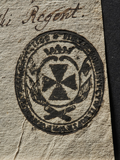 Seal of the Civil-Military Order Commission of the Braclaw Voivodeship and County; seals attached to documents. Oval ink print of the seal: on an oval crowned shield, a knight's cross—the coat of arms of the Braclaw Voivodeship—surrounded by a panoply. Illegible inscription on the rim. 1790, Poland., A close-up of textured beige paper showing a dark circular emblem printed in black ink; the emblem contains a central geometric cross-like shape surrounded by laurel-like branches and a small crown motif above, with a thick outer ring and irregular worn areas in the ink; the paper has visible creases and fiber texture, and a narrow black vertical strip appears along one edge.