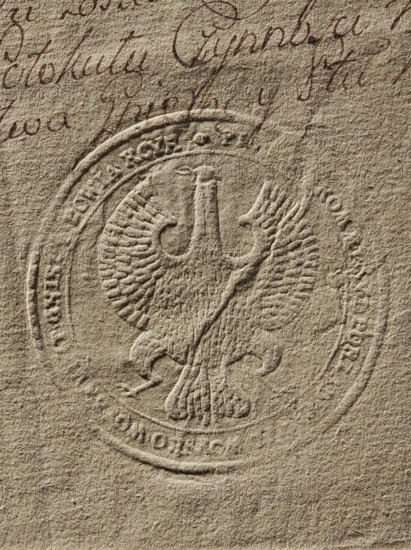 Round seal impression of the Civil-Military Order Commission of the Gniezno Voivodeship and Kcynia County. Eagle without a crown. In the rim, the inscription: PIE. KOMMI. ORDER. CIVIL. MILITARY. VOIVODESHIP. GNIEZ. COUNTY. KCYN. 1790, Poland. Seal of the Civil-Military Order Commission; seals with coat of arms and eagle; documents; official seals., A textured beige surface with an embossed circular seal featuring a stylized bird with outstretched wings and a central vertical element; the embossed area shows raised ridges and feather-like grooves; above the seal there is cursive handwriting in a dark brown ink; overall colors visible are beige, light tan, and dark brown.