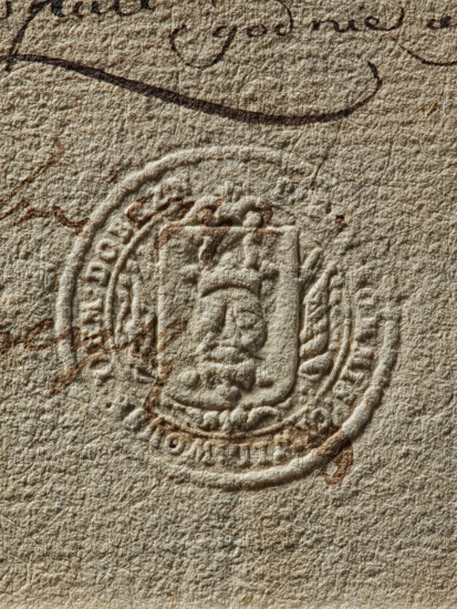 Round seal imprint of the Civil-Military Order Commission of the Dobrzyn Land. On the shield, the coat of arms of the Dobrzyn Land — a head between two crowns. Behind the shield, a panoply. Around the rim, the inscription: KOMMIS : CIWIL. WOYSK. ZIEM.DOBRZN., 1792, Poland., A close-up of textured beige paper showing an embossed circular seal with a shield-like emblem in the center and decorative elements around its edge, faint brown ink marks and pen strokes across and near the seal, and variations in the paper fibers and shadows creating a rough, tactile surface with colors including beige, brown, and off-white.