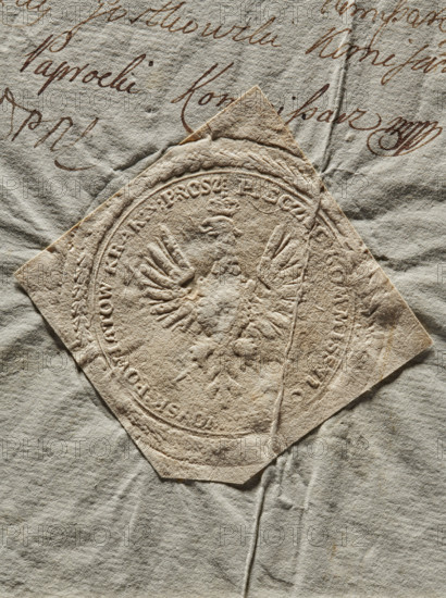 Round imprint of the seal of the Civil-Military Order Commission of the Kraków Voivodeship, Proszów County and the Duchy of Siewierz. Polish eagle with a crown. In the rim the inscription: PIECZEC KOMMISSYI : CYWIL : WOYSK : POWIATOW : KRAK : Y : PROSZ., 1792, Poland, seal, A close-up of an aged, textured paper surface showing a roughly diamond-shaped embossed seal pressed into the paper, with visible raised and indented ridges forming a decorative emblem and surrounding circular border; the paper shows creases, folds, and small tears and has a rough, fibrous texture. The background paper has a wrinkled appearance with flowing cursive markings partially visible but not described. Visible colors include shades of beige, tan, cream, off-white, light brown, and a few darker brown ink strokes.