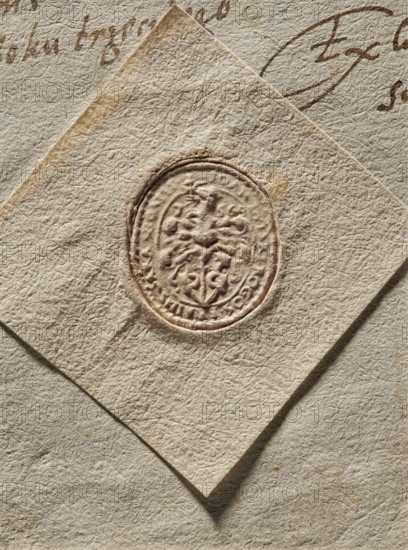 Signet ring seal of Jan Dulski, starost of Rogozin and Bransk; fl. ca. 1576. Oval dry impression of the signet ring seal. In the central field, on the rim, the Przegonia (Przegon) coat of arms with very rich labres. The inscription on the rim is partially illegible: IOAN DULSKI ROGOS . BRAINS, 1576. Poland. Seal. Dimensions: 1 — 21 mm; 2 — 23 mm., A close-up of textured, off-white paper with a slightly darker, square-shaped piece of paper placed diagonally on top; the top piece features an embossed oval seal with intricate raised patterns and decorative motifs, creating shadows and highlights; the surrounding paper surfaces show visible fibrous texture, creases, and subtle variations in beige and cream tones; there are traces of brown ink strokes partially visible at the edge of the image.