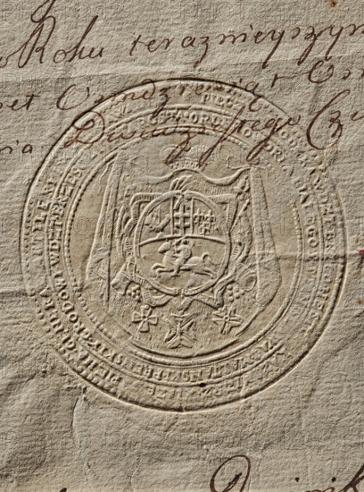 Seal of Nestor Casimir X Sapieha, Starost of Brest-Litovsk. Round dry impression of the seal. The Lis coat of arms within a multi-field cartouche on an ermine cloak under a mitre. Three orders below the shield, behind it a panoply. Along the double rim an inscription: PIECZEC GRODZKA . WDZT . BRZ . CONEST, KAZIMIERZ . IIAZE . SAPIEHA. GENERAL. OF ARTILLERY. GRANTED KNIGHT OF THE ORDER OF THE WHITE EAGLE. OF STANISLAW. I MALTA, . Y. CASTLE. WDZT. BRZESC LITHUANIAN. STAROST. 1788, Poland., A close-up of textured beige paper showing an embossed circular seal with intricate heraldic designs, including a central shield with decorative elements and surrounding ornamental borders; there is brown ink handwriting partially overlapping the upper part of the seal and a few small brown ink marks near the lower edge; visible colors include beige, tan, and brown.