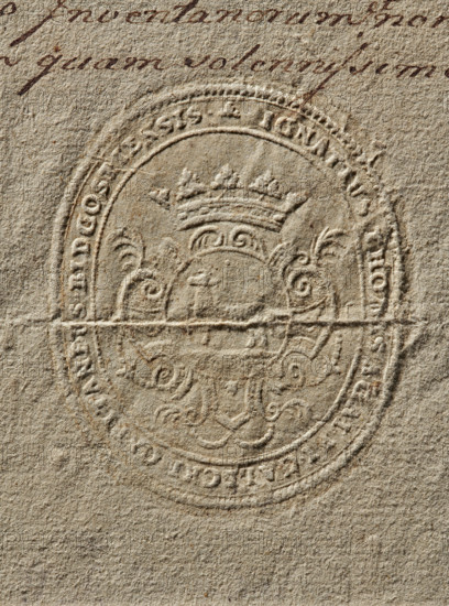 Seal of Ignacy Tomasz Galecki, Starost of Bydgoszcz. Oval dry impression of the seal. The Junosza coat of arms in a decorative cartouche under a crown. In the rim is the inscription: IGNATIUS THOMAS A. GALEI GALECKI CAPITANEUS BIDGOSTIENSIS. 1766. Poland. Seal. Dimensions: 47.2 mm and 57.4 mm., The image shows a textured beige surface with an embossed oval seal featuring decorative scrollwork and a crown motif; the seal creates raised and recessed areas casting subtle shadows, and there is a small area of brown handwritten ink visible near the top edge.