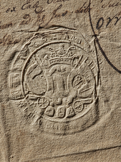 Seal of Antoni Weglenski, Starost of Chelm. Antoni Weglenski (fl. ca. 1769); Witold Zurakowski (?-1927). Document seal; coat of arms seal; Szreniawa coat of arms; private seal; seal of a starost. Round, dry impression of the seal of Antoni Weglenski, Starost of Chelm. On the decorative shield the Szreniawa coat of arms, behind the shield rich panoplies. Partially illegible inscription on the rim: 'ANTON, CAPITANEUS AD 1769'. 1769, Poland., A textured beige paper surface with an embossed circular seal featuring a crowned emblem in the center, surrounded by ornamental shapes and curved bands; there is dark brown ink handwriting partly visible near the top and right edges, and the overall colors visible are beige, tan, brown, and darker brown shading.
