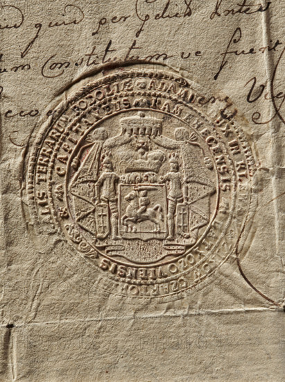 Round seal impression of Prince Adam Czartoryski, Starost of Kamieniec. Shield with the Pogon coat of arms under a mitre, supported by two knights placed on an ermine tent. Inscription on the double rim. 1765, Poland., A close-up of an embossed circular seal pressed into aged beige paper showing fine raised details and textured creases; the seal contains a central heraldic shield with a mounted figure and surrounding decorative elements including two standing human figures, drapery, and a crown-like motif, all rendered in the same tan and light brown tones as the paper; the background shows handwritten cursive strokes in dark brown ink partially visible around the seal, with darker shadows and slight reddish-brown accents where the embossing is deeper, and the paper surface displays fibrous texture, folds, and subtle discoloration in shades of beige, cream, and light tan.