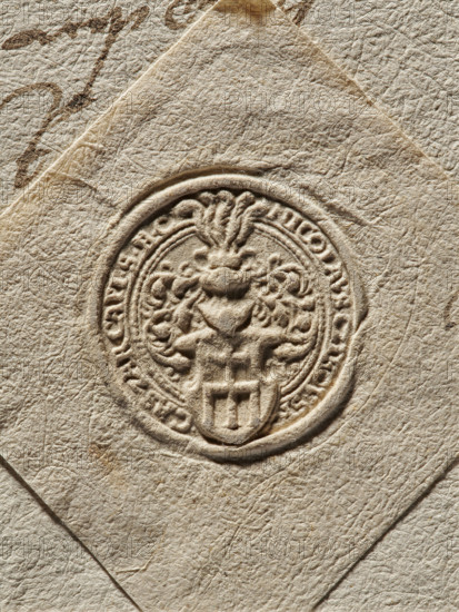 Seal of Mikolaj Cikowski of Cikowice, Starost of Sanok. Round seal impression. Shield with the Radwan coat of arms with rich lambrequins. In the crest above the crowned helmet are five ostrich feathers. In the rim, interrupted by the coat of arms and the crest, is the inscription: NICOLAVS CZIKOWSKI // CAS. ZAR. CAPI S., . C, 1564, Poland., The image shows a close-up of textured beige paper with an embossed circular seal pressed into it; the seal features a raised ornamental crest with floral and scroll-like elements and a shield at its base, all rendered in the same beige tones as the paper, with shadows and highlights accentuating the raised design; the surrounding paper displays a fibrous, wrinkled surface with a few darker brownish smudges and subtle variations of cream, tan, and light brown across the scene.